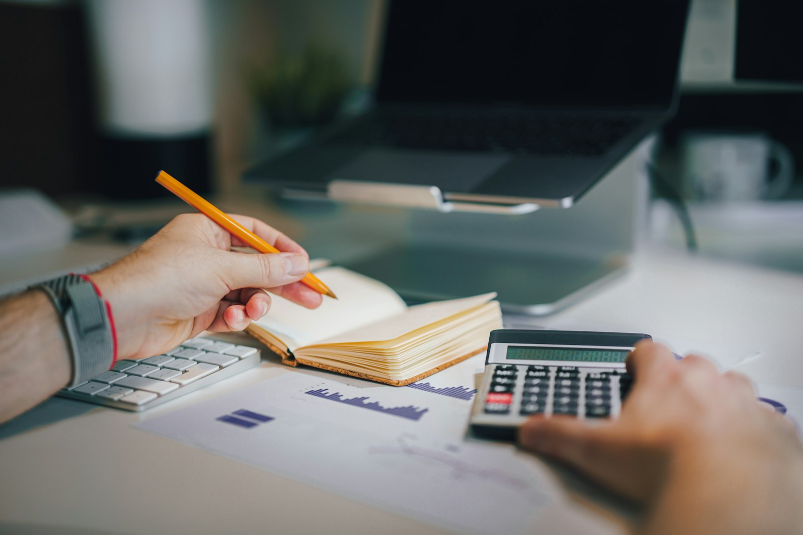 A bookkeeper working with a calculator and a laptop